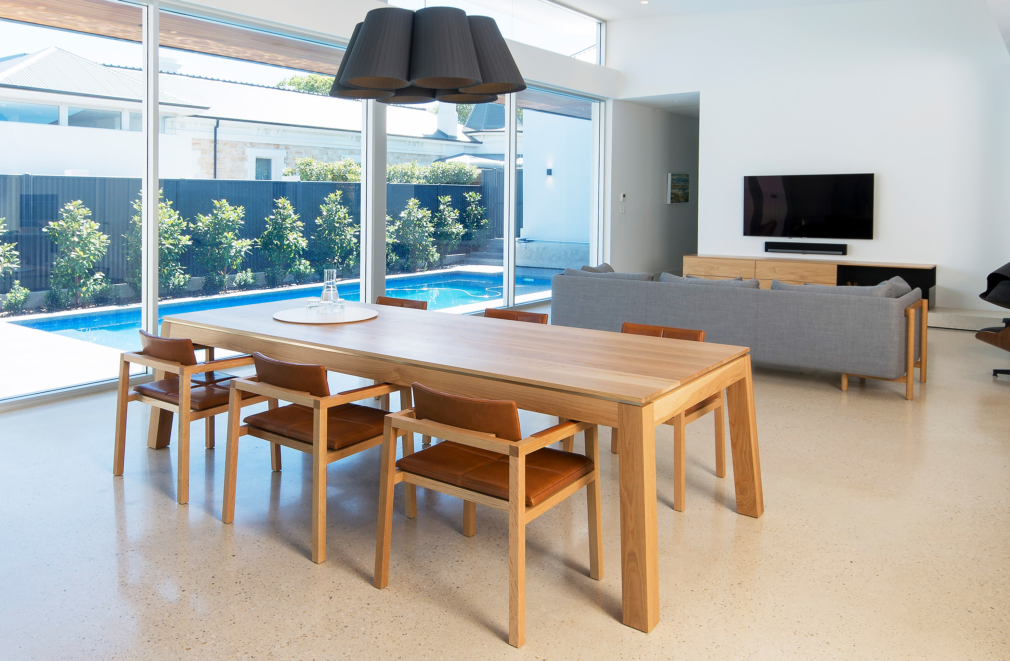 Sweeping view into this modern family home evoking a sense of calm as you move past the solid oak designer dining table by FrancoCrea onwards to the sensation family pool backdrop