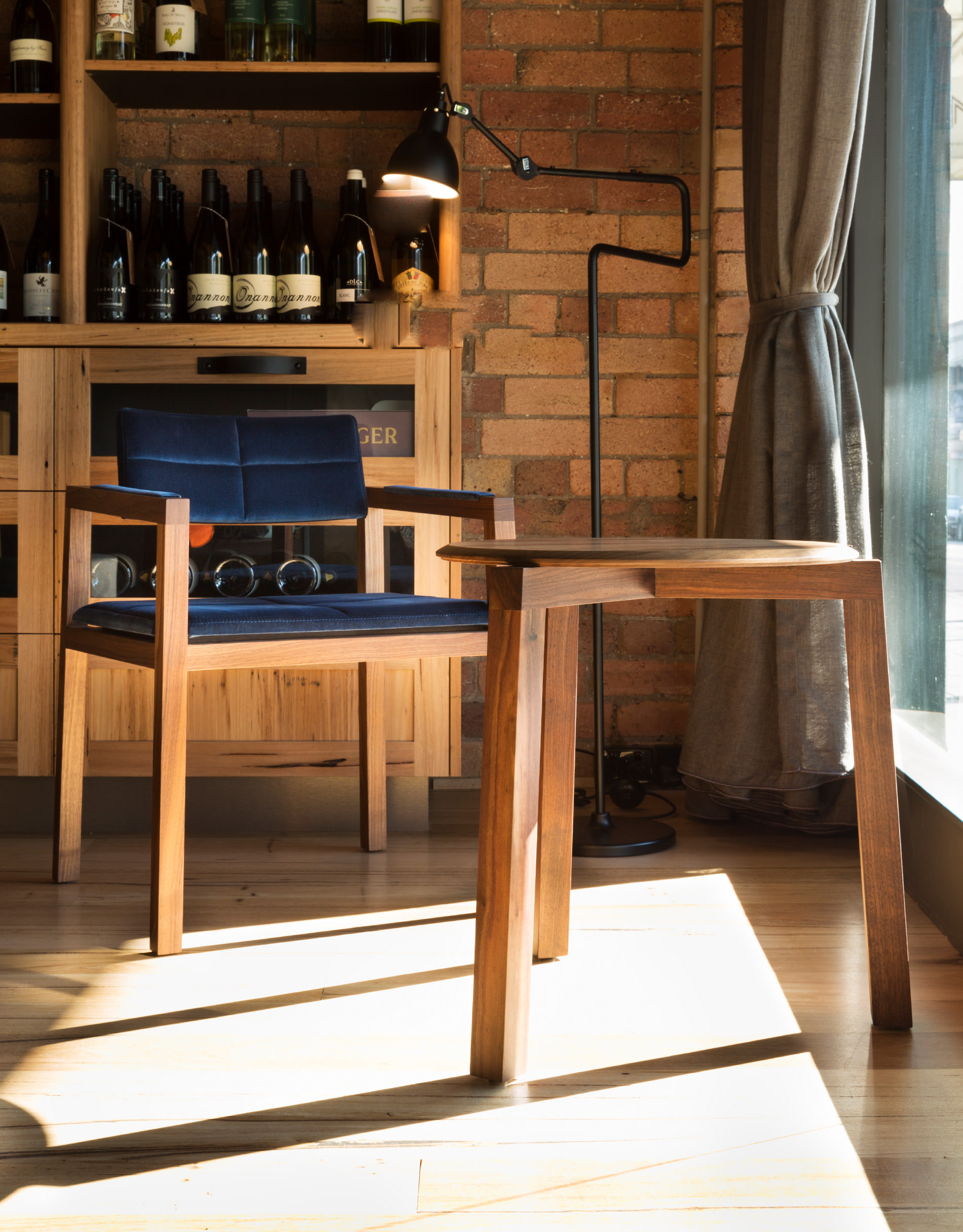 Solid cream brickwork, warm timber floors and a wine cabinet behind the designer dining chair by Australian designer Francocrea all come together to create a wonderfully inviting space to relax
