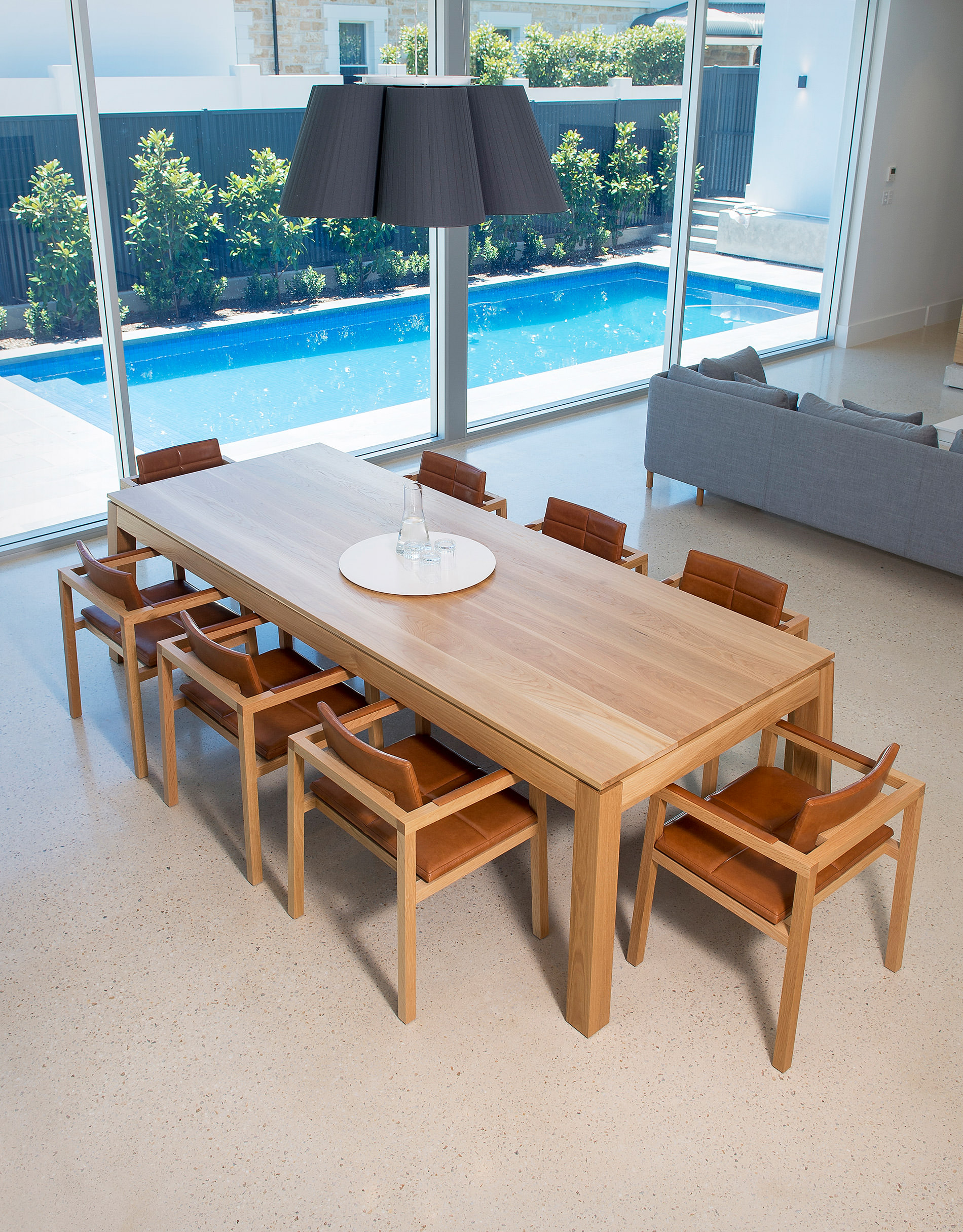 Such an airy open dining room shown here with stunning solid oak designer dining table and chairs featured with a glimmer of spectacular blue in the family pool behind