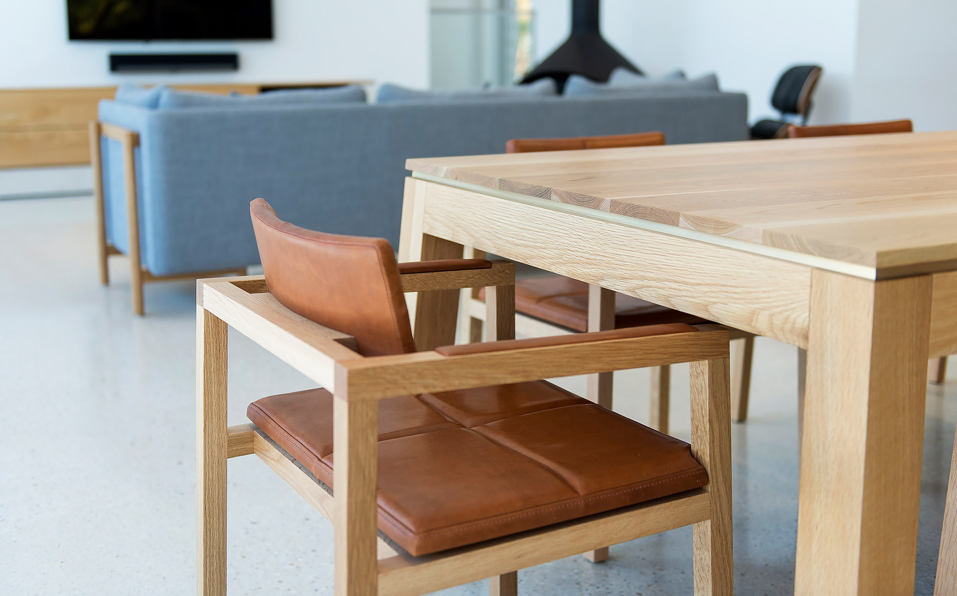 The alluring warmth of the wood fireplace is just visible behind the designer dining table by Australian designer FrancoCrea in this luxury family home