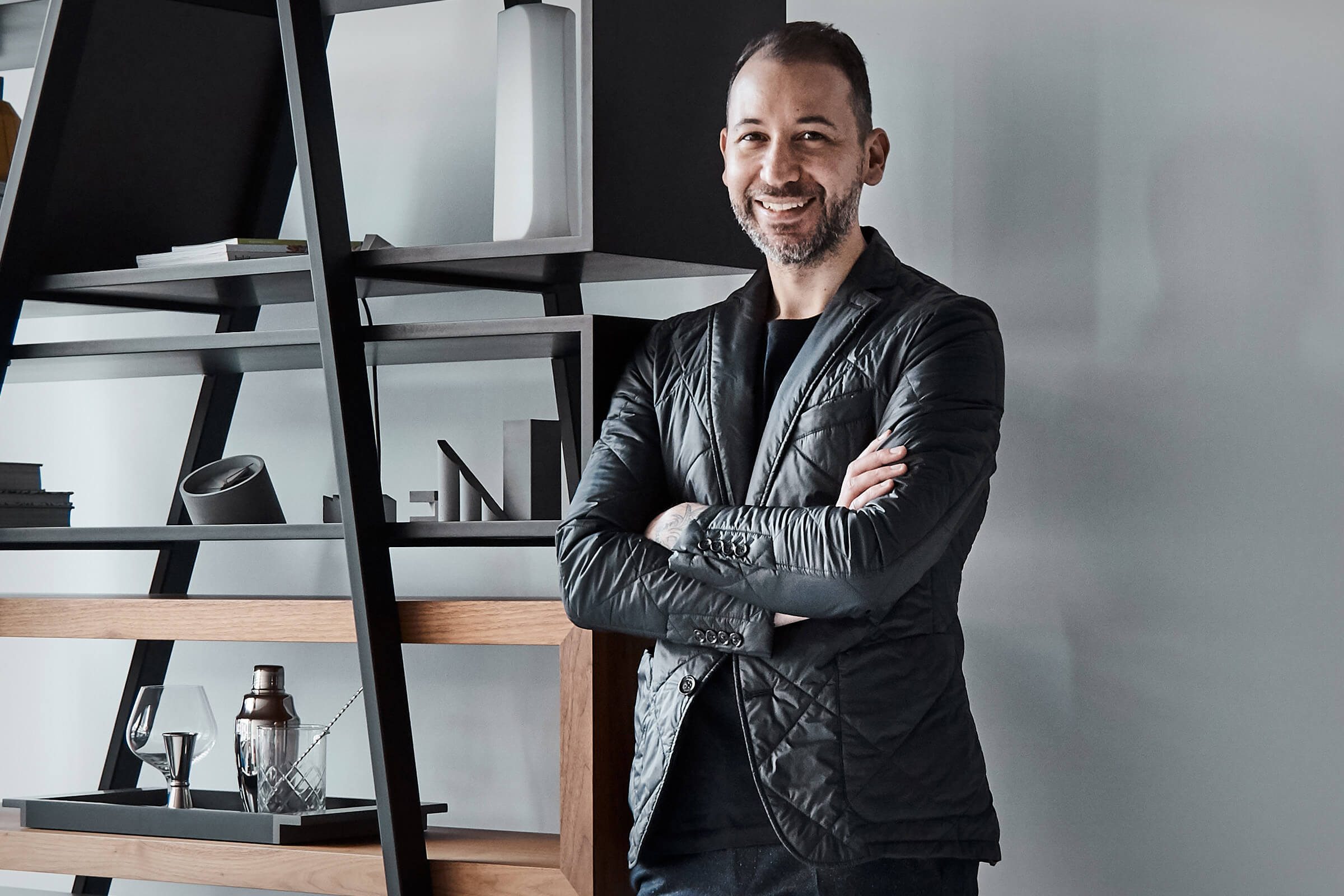 Furniture designer Franco Crea standing next to his Ekta shelf smiling in his Melbourne showroom